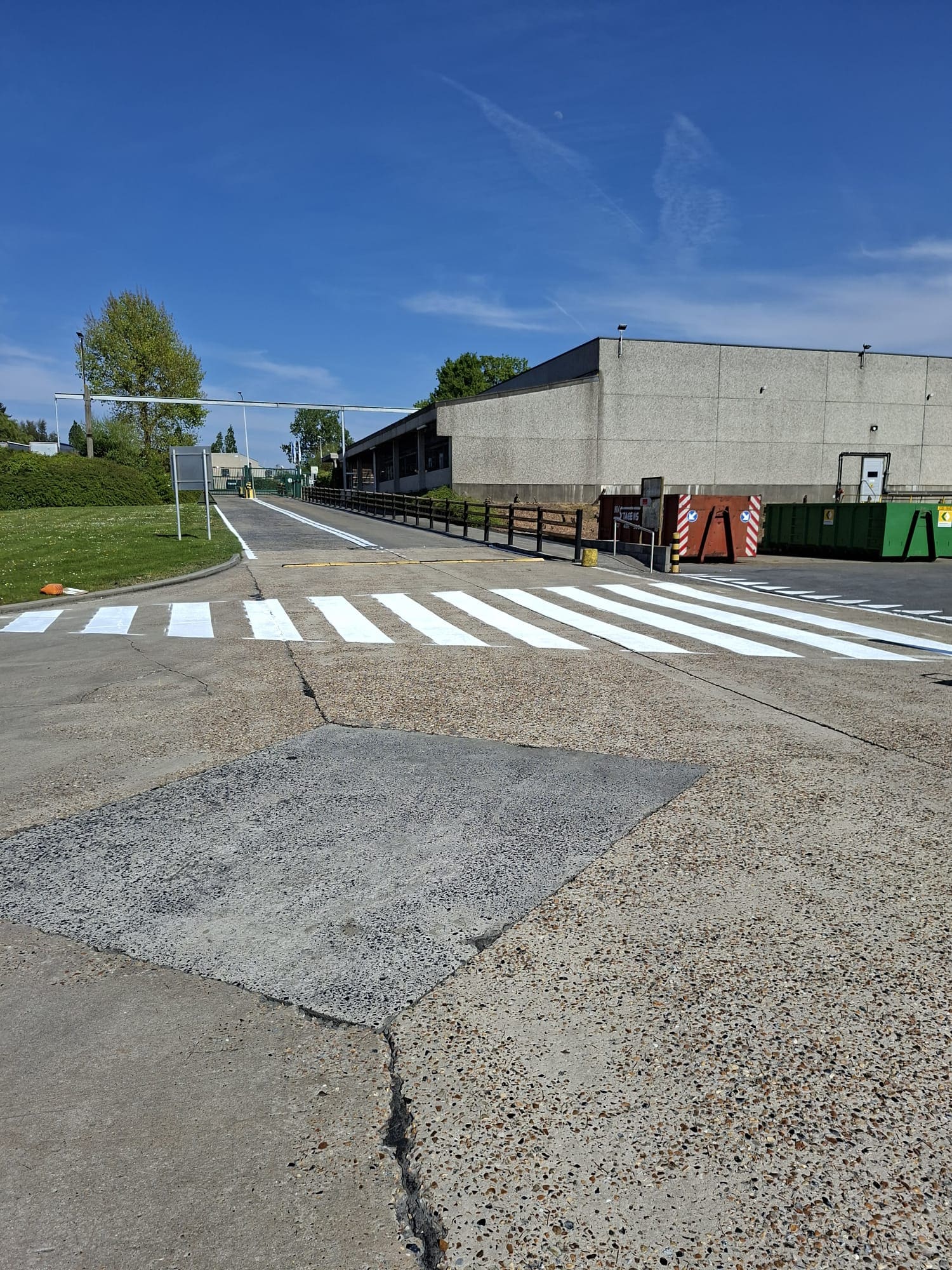 Vers wit zebrapad op betonnen toegangsweg van een industrieterrein